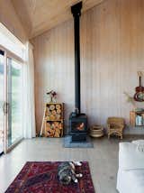 The restrained 820-square-foot interior is defined by the angular ceiling. Garlick left the prefabricated structural panels unfinished to save on material costs. A True North wood stove from Pacific Energy heats the house. Max, the family’s cat, naps on a vintage rug purchased on eBay.