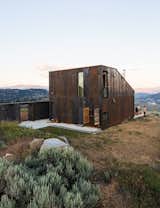 Architect Jesse Garlick’s rural Washington vacation home references its rugged surroundings. The steel cladding has developed a patina similar to the ochre-red color of bedrock found in the area.