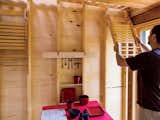 Daniel hangs a folding chair, Shaker style, on the wall adjacent to the entrance. The room gains extra light through slivers of space between the slats of the floor above. Structural two-by-fours and framing were left raw. 