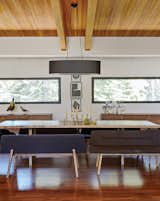 A wood slab table is paired with bench seats from De La Espada and a vintage brass candelabrum in a family home near Lake Tahoe. The credenzas are Bo Concept. An oversize oval black linen shade from Dogfork Lamp Arts hangs above a table Maca created out of a wood slab from West Marin-based artisan Evan Shively of Arborica. The brass candelabrum is vintage, sourced from 1stDibs.