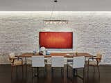 The brick wall adjacent to the custom dining table by Brooklyn-based Uhuru Design is original to the structure. 590BC and its team spent months trying to find the right translucency for the whitewash covering the brick. "We call it the 'selective loft' because of the contrast of the refined materials and cabinetry against the industrial materials of this former light bulb factory," says Breitner. Photo by Frank Oudeman.