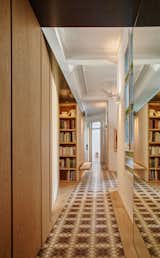 Typical of historic homes in Eixample, the apartment's rooms are laid out along two central corridors that meet to form a 'V' shape. The firm's update to the space centers around the addition of an oak cabinet wall, which adds generous storage to the narrow floor plan.