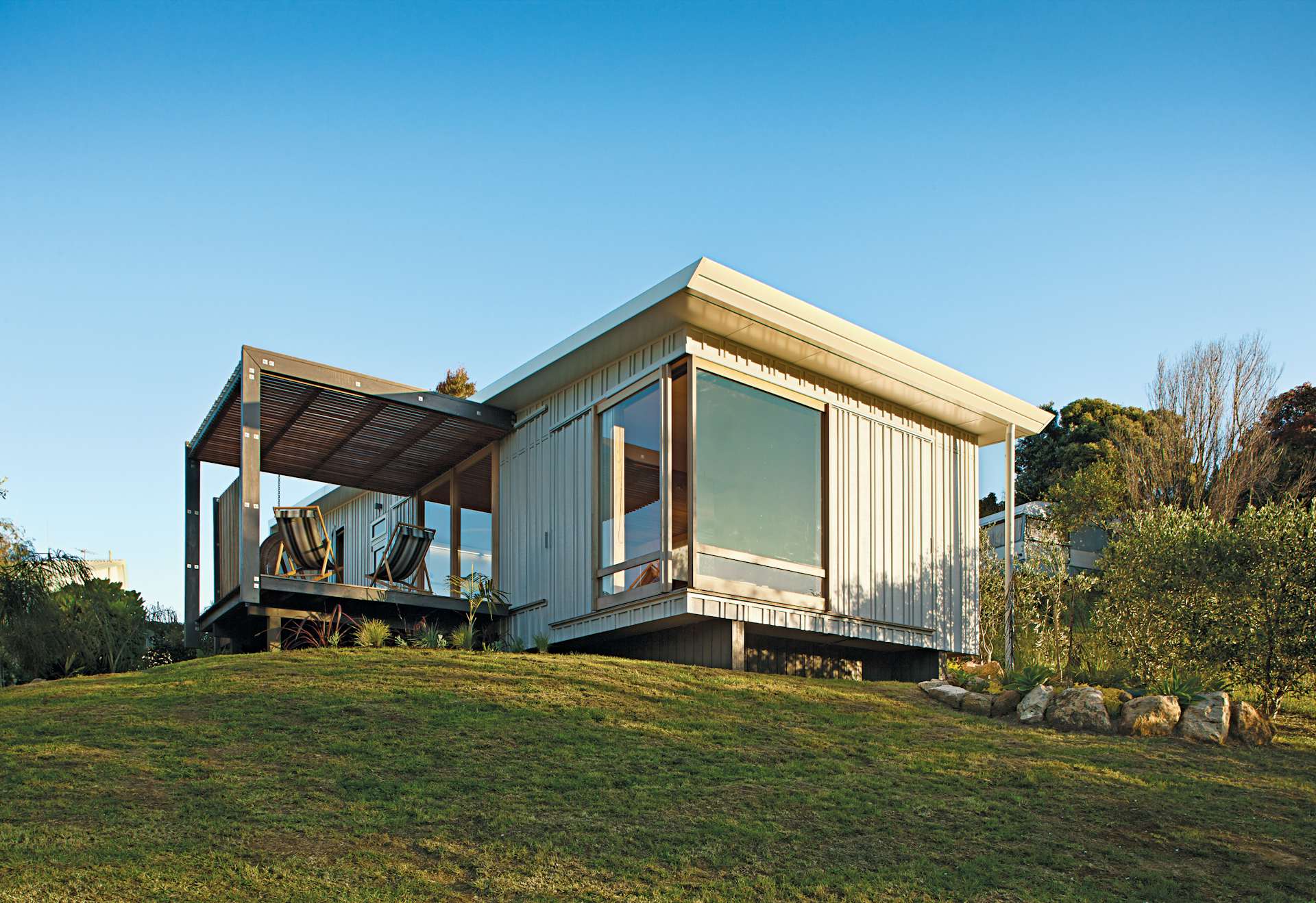 This compact prefab vacation home in the seaside community of Onemana Beach in New Zealand was a designed and built in collaboration with architecture students from Auckland’s Unitec Institute of Technology.  