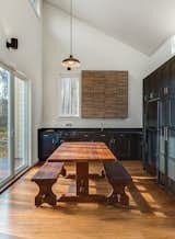 To keep costs down elsewhere (the house was built for just over $118,000), architect Brun and his partner Lizmarie Esparza specified Ikea kitchen cabinets and a black refrigerator, which is less expensive than stainless steel. "It was really important that the kitchen opened up to the outside deck. Its designed in an L-shape with an indoor-outdoor table," Brun says. "The idea is that when you open the door, there's a continuous environment connecting the inside with the outside—it's as open as possible." Gordon purchased the hand-crafted solid teak antique table from Indonesia.  Photo 2 of 6 in How to Build an Off-the-Grid Cabin in Arkansas for just over $118,000