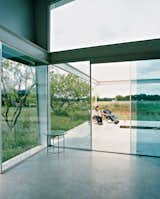 A continuous concrete slab runs from inside the house out to the open deck, which is exposed to the wind that sweeps the surrounding fields.