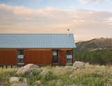 The fire-resistant structure is clad in corrugated Cor-Ten steel that has been left to rust for easy maintenance. Instead of fussy landscaping, the family spread seed for native grasses and wildflowers that they let fill in naturally.