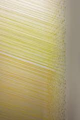 A detail shot of Slant Yellow (2010). Staples are used to hold the pieces of Egyptian cotton thread together.