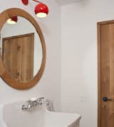 Nico shares the downstairs bathroom with any overnight guests who may be visiting. The circular mirror, framed in white oak, was designed and made by Materia Designs, based in Kerhonkson.  Photo 6 of 10 in An Enclave of Modern Cottages in New York's Hudson Valley