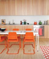 In this custom-built London guesthouse kitchen designed by Studiomama, lustrous vertically clad cabinetry achieves additional depth with the addition of the chairs, which were picked up for $15 each at a local market and powder coated in bright orange.