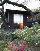 The two-story house is wrapped in redwood. Its box-like form would become one of the architect's signature design moves. A large double-height window in the living room provides views of the surrounding foliage.