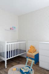Although the color palette is minimal, the couple added bursts of blue and yellow throughout the home in the living room and even the new nursery.  Photo 1 of 19 in 23 Cool Cribs for the Modern Baby from Expecting Couples Will Understand, Storage Is Everything at This Apartment