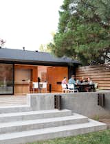 Outdoor, Wood Patio, Porch, Deck, Concrete Patio, Porch, Deck, Large Patio, Porch, Deck, Wood Fences, Wall, Back Yard, Grass, and Horizontal Fences, Wall IKEA chairs join a table from CB2; a Kawneer triple-sliding door opens to the family’s new ipe deck.  Search “New-Grass-Roots.html” from A Completely Dysfunctional Nevada Kitchen Becomes Everyone’s Favorite Spot for Parties