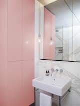 In a bathroom otherwise dominated by the neutral tones of Statuario marble, a powder-pink wall of cabinetry adds a colorful contrast—and creates ample storage to boot.