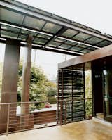 Outdoor and Small Patio, Porch, Deck A steel-beam canopy with solar panels shades the house and provides electricity.  Search “panel house” from Solar Inspiration