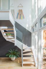 The back staircase abuts a glass facade overlooking the backyard, allowing plenty of light into the kitchen area above. The art hanging on the wall is by artist Julie Thevenot.