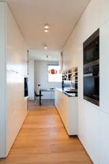 Two custom built-in structures form a corridor-like workspace in the kitchen. The appliances are by Miele, and the steel-and-black glass sink is from Franke.  Photo 2 of 5 in A Light, Bright Apartment Renovation in Barcelona by Aileen Kwun