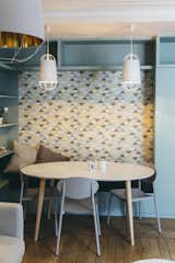 Graphic wallpaper complements the color scheme and adds visual interest. Adding bench seating and built-in shelves around the La Redoute table helps to delineate this space as a study and dining area within the larger room.