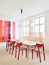In the dining area of the kitchen, a Mobile Chandelier 3 by Michael Anastassiades is suspended above a table from local cabinetmaker Københavns Møbelsnedkeri. Vintage red dining chairs by Ralf Lindberg mingle with an Ilse Crawford bench for De La Espada. Photos courtesy the Apartment.
