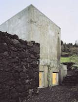The new concrete exterior has already been transformed by the rain and humidity of the Azores, and now sports an aged look. The color contrasts with the basalt wall and dark soil of the Ilha Preta ("Black Island"). Vieira da Silva anticipates that surprising patterns and textures will develop on the outer walls over time.