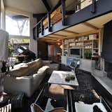 A loft floor looks over the living room which in contrast to the slate flagstone, uses steel plate flooring.