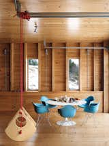 A swing made by architect Christopher Campbell flies high in his Maine retreat alongside modern classics like a Saarinen Tulip table and Eames shell chairs that pop against the wood paneling.