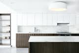 In the sleek kitchen, the white Ikea cabinet uppers seem to disappear into the wall, while the bases get a distinctive custom walnut wrapping. Flanking the cabinets are open bookshelves, which provide secondary function as a spacial divider for the children’s play area. A Dornbracht faucet sits on a slab of Vermont Olympian White Danby marble, which is also used for the island and backsplash.