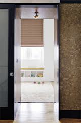 On the second floor, the sliding door to one of the kids’ bedrooms lies flush with a cork-wrapped wall. In the bedroom, a colorful custom Maharam window shade rests above a window seat with a Kvadrat cushion.