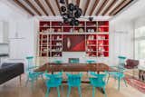 A quartet of red paints (Raspberry Truffle, Million Dollar Red, Vermillion, Arroyo Red), all by Benjamin Moore, make the built-in shelving in the dining area pop. The table is a custom design made of bookmatched walnut slabs joined by lacquered butterflies. The chairs are vintage Paul McCobb lacquered in turquoise (Benjamin Moore's Aruba Blue). The Ligne Roset Ruché sofa, designed by Inga Sempé, separates the living and dining spaces. The chandelier is by David Weeks Studio.