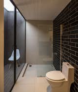 “The water waste from the shower and the kitchen irrigate the interior garden,” LLaumett says. “The toilets have their own patio, which provides them with ventilation and natural light.” Black Marazzi tiles cover the wall.