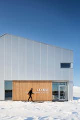 Last year, architecture firm Microclimat completed a rigorously modern fitness center in the city of Waterloo, Ontario. The asymmetrically gabled structure rises from the wintery landscape, sporting a palette of steel, cherry wood, and red cedar.