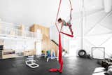 Here, the high ceiling, a style borrowed from industrial lofts, serves a utilitarian purpose. Gymnast rings hung overhead allow athletes to suspend themselves 25 feet in the air.