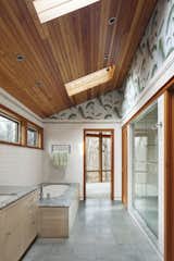 For the master bathroom, Moser installed a green marble bath top and green onyx floor tiles. Details such as in-floor heating, an Americh Madison bathtub, and GROHE sink make for a comfortable space.  Photo 1 of 5 in Bathroom by Eric Kt Lau from After a Fire, a Midcentury Home Rises from the Ashes