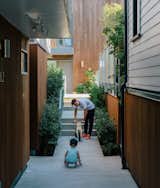 Resident Misha Bukowski plays with young Zachary in the walkway between the renovated buildings. The new units are clad in stained local cedar.