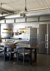 Kitchen, Refrigerator, Undermount Sink, Ceiling Lighting, Pendant Lighting, and Range In a loft renovated by designer Andrea Michaelson, a Liebherr refrigerator blends in with stainless-steel cabinets from Fagor. Flow chairs by Henry Hall Designs and CB2 benches pull up to an antique farm table.  Photos from Steel and Brass Cover Nearly Every Surface of This Industrial L.A. Kitchen