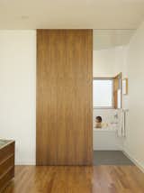A custom walnut sliding panel door closes off the bathroom. The tub is lined with Heath tile.