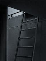 An adjustable ladder, which blends in with the walls in Vipp's signature ebony powder-coated steel, leads up to the sleeping loft.