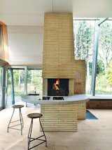 The open-plan home’s core is the towering chimney—clad in the same double-long, thin bricks that sheathe the Kolumba museum in Cologne, Germany. It holds three fireplaces, a conventional oven, and a pizza oven; all vent into three distinct flues, emerging from the chimney as their own kind of architectural statement. Inside, life revolves around the brick chimney, which the architect surrounded with a concrete counter that wraps from the kitchen to the living area. The stools are vintage.