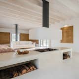 On an agricultural estate in Portugal, Blaanc Studio designed a simple retreat that does its utmost not to interfere with the scenic backdrop. The home was built with rammed earth, which is known for its thermal properties that help maintain a mild temperature all year long. A large, open fireplace with plenty of wood storage is used to warm the living area in winter. The firewood storage's open shelving is carefully located on the side of the island that doesn't face the living room, making sure that it is only visible in certain locations.
