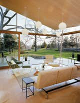 Entire walls of floor to ceiling windows make it difficult to tell where the house ends and the outside begins in this modern farmhouse living room. The Kelleys furnished the cottage with help from Suzanne’s daughter Betsy Burbank of Betsy Burbank Interiors. Classic modernist icons, such as a Saarinen Womb chair for Knoll, a Herman Miller Eames lounge chair, and an Eileen Grey E1027 side table look at home alongside present-day pieces such as an Encore sofa (which handily folds down into a sleeping surface) from Room &amp; Board and a Doka rug designed and produced by Stephanie Odegard.&nbsp;