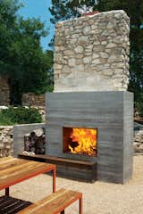 This outdoor fireplace in Austin, Texas is generously sized and created out of board-formed concrete, with a spot directly adjacent for firewood storage and a wood shelf running in front for added storage.