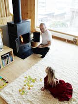 Living Room, Wood Burning Fireplace, Standard Layout Fireplace, Light Hardwood Floor, Rug Floor, and Storage Architect Per Bornstein and his daughter Velma relax in the living room. The woodburning stove was a second-hand store find. Photo by Pia Ulin.  Photo 3 of 25 in Knotty by Nature