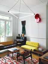 Located just off the entry hall, this room opens onto a lush garden. The residents commissioned the overhead light from designers Sylvain Willenz and Hubert Verstraeten. “The use of red billiard ball references Charles and Ray Eames’s Hang-It-All coat rack,” says Smith. The wall-hung light is by the contemporary São Paulo–based designers Luciana Martins and Gerson de Oliveira. The rug is a Moroccan patchwork from the 1960s; the teak-and-leather Kilin chair is by Sergio Rodrigues; and the cane-backed sofa is a student daybed designed by Hans Wegner for Getama in the 1950s.