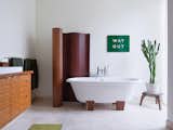 The master bathroom has a bamboo screen and a Deauville tub by Victoria + Albert. A vintage enameled metal sign from the London Underground is framed by the screen and a cactus that sits atop an African stool. Read more about  the eclectic South Minneapolis residence here.  Search “Bathroom” from Rooms Filled With Vintage Finds 