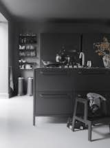 Kitchen and Painted Wood Floor The iconic waste bin that gave Vipp its start is a mainstay in the Egelunds’ home, as are many of the company’s streamlined design solutions. The waste bins, shelves, glasses, and ceramics are by Vipp.  Photo 2 of 5 in All-Black Kitchens by Luke Hopping from Black, White, and Gray All Over: Monochromatic Copenhagen Townhouse