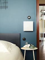 Farrow & Ball’s Hague Blue covers a wall in another bedroom. The light switches here, and throughout the apartment, are Hager’s 1930 series. Deau stationed a 1970s-era sconce next to the bed.