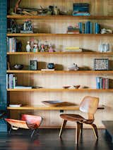 A vintage Molded Plywood Lounge Chair (LCW) by Charles and Ray Eames for Herman Miller sits in front of built-in shelving in untreated hemlock.