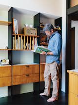 Resident Ty Milford peruses a book by the George Nelson–inspired built-ins fabricated by Big Branch Woodworking