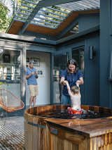 Kelly Milford helps son Adam out of the hot tub nestled on a wood deck in back of the house. The exterior paint is Wrought Iron by Benjamin Moore.