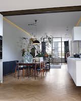 The living room, dining room, and kitchen are arranged in a 60-foot-long enfilade. The pendant light above the table is Nemo by Franco Albini for Cassina. A grouping of succulents and Monstera deliciosa plants act as a natural room divider.