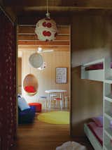 Kids Room, Playroom Room Type, Lamps, and Bedroom Room Type The couple’s ten-year-old twins have connecting rooms next to a play space furnished with Aalto stools, a table from Artek, and a Nanna Ditzel rattan hanging chair purchased at Interstudio.  Search “kaktus-stool-by-enrico-bressan.html” from Local Wood Clads Every Surface of This Idyllic Australian Getaway